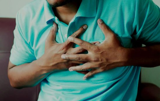 Male With Both Hands On Chest Experiencing Chest Pain