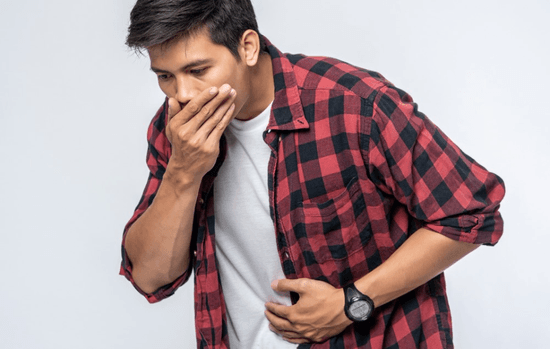 A man standing with dyspepsia, putting a hand on his stomach and another hand to cover his mouth. 